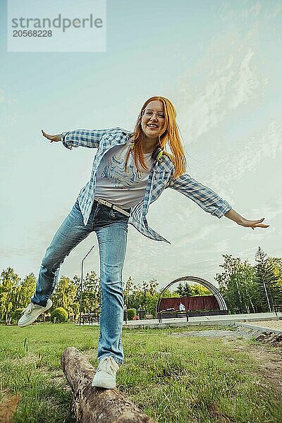 Playful teenage girl balancing on log at public park