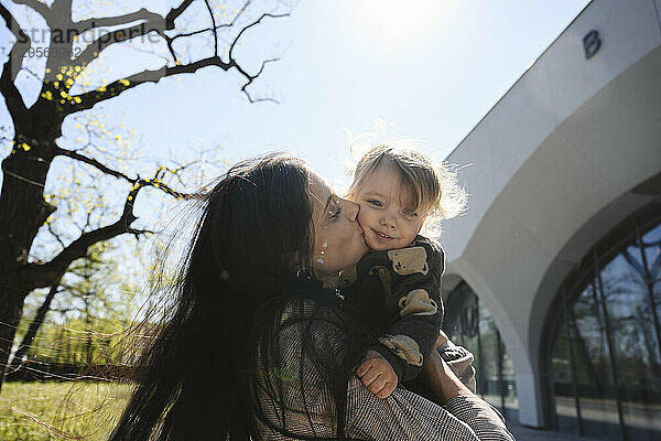 Mother kissing son at sunny day