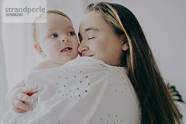 Happy mother embracing baby boy at home