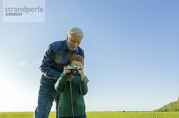 Boy taking picture on old camera with his grandfather