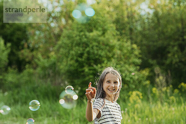 Happy girl playing with soap bubbles at back yard