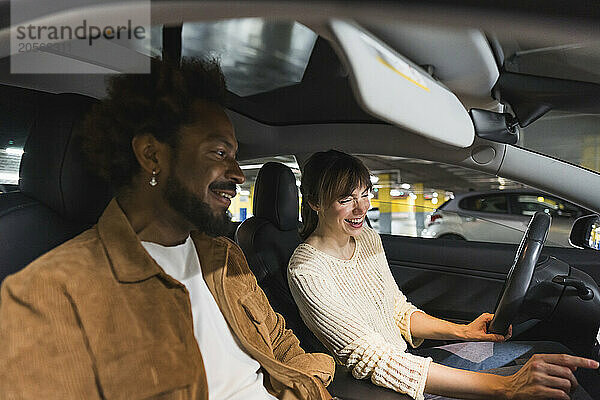 Happy couple sitting in car at parking garage