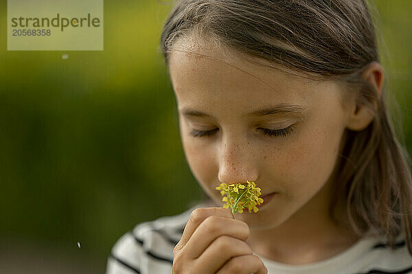 Girl with brown hair sniffing flower