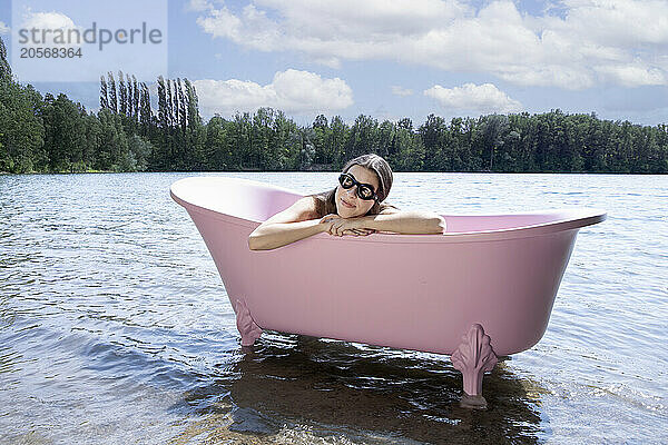 Girl wearing swimming goggles and relaxing inside pink bathtub