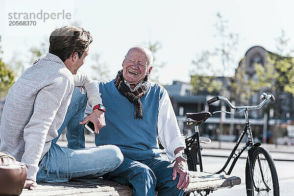 Cheerful senior man talking to grandson on sunny day