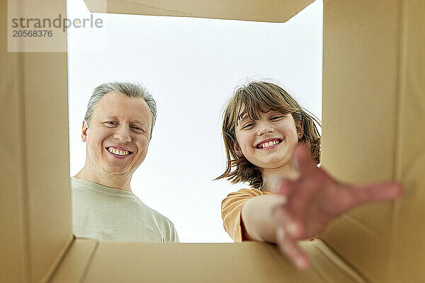 Dad with daughter looking into brown cardboard box