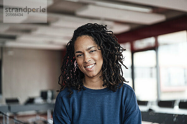 Smiling young businesswoman with dreadlocks at office