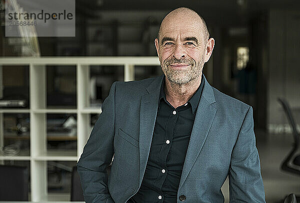 Confident businessman with stubble wearing blazer in office