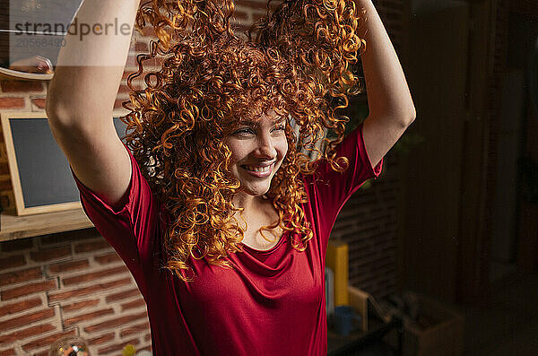 Cheerful curly hair woman playing with hair at home