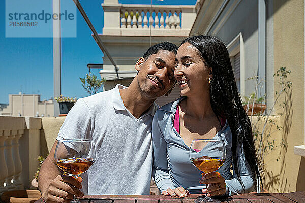 Happy young couple with eyes closed sitting at terrace on sunny day