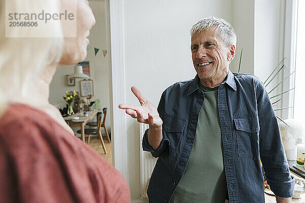 Happy senior man talking with retired woman at home