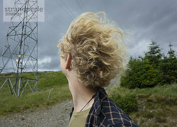 Young man with tousled hair looking over shoulder in Scottish Highlands