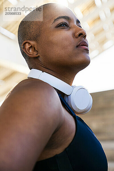 Thoughtful sporty woman with wireless headphones