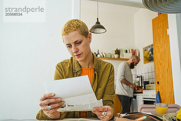 Blond freelancer reading letter sitting at home office