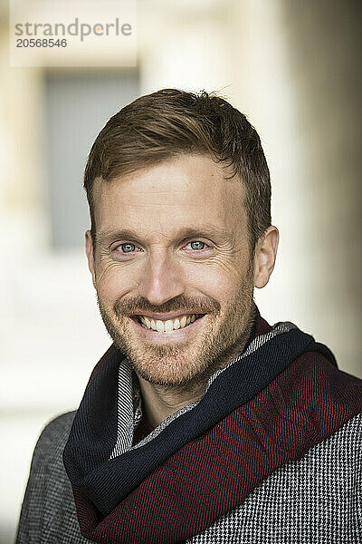 Smiling man with hair stubble and wearing scarf