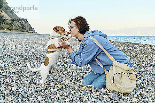 Woman spending leisure time with Jack Russell Terrier at beach