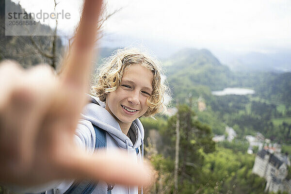 Smiling boy making letter L on mountain near Neuschwanstein castle