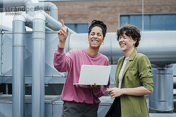 Cheerful businesswoman pointing by manager near machinery