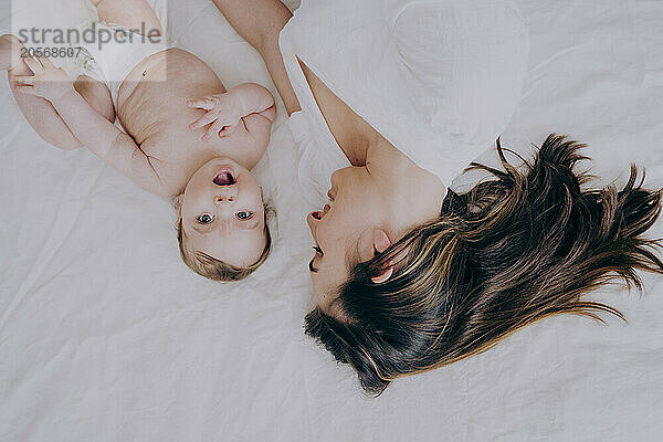 Happy mother lying on bed with baby boy at home