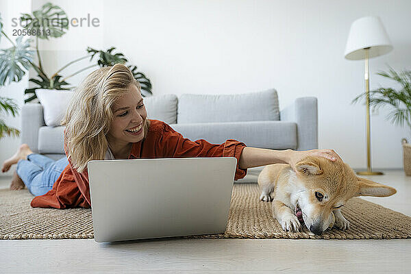 Freelancer lying on floor and stroking dog at home