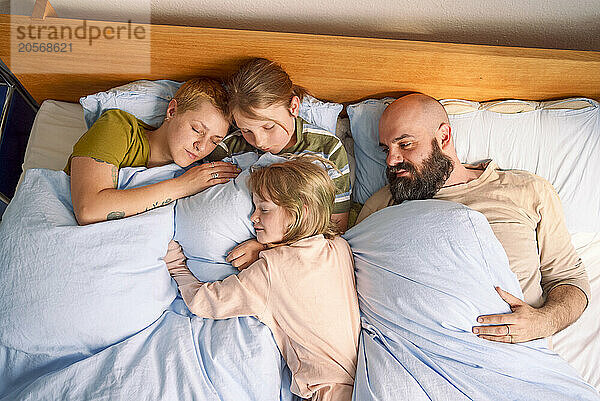 Family sleeping together on bed at home