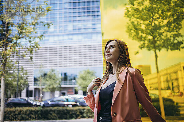 Confident woman with long hair walking on street near building