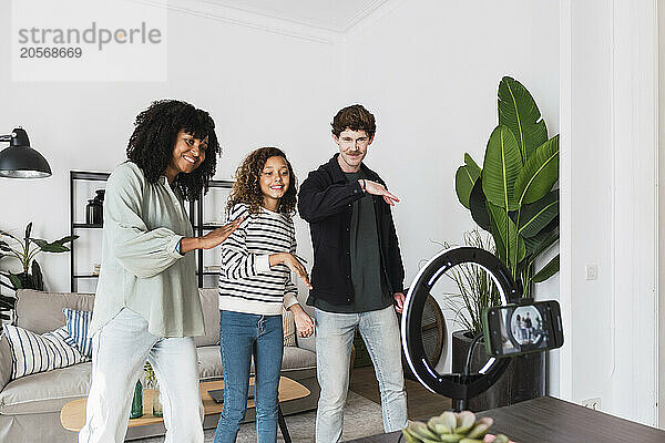 Happy family filming funny video in living room