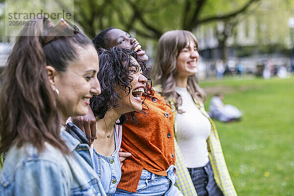 Cheerful multiracial friends walking side by side at park