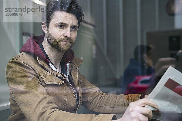 Thoughtful man sitting with magazine in restaurant