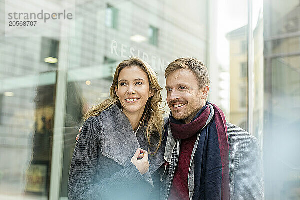 Smiling man with arm around girlfriend in city