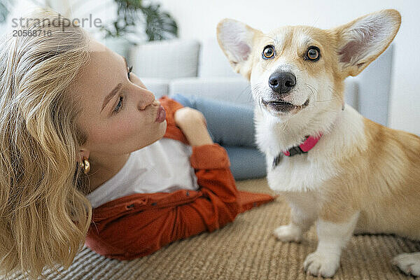 Woman puckering lips near dog at home