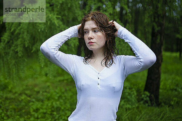 Young woman with hand in hair standing in forest