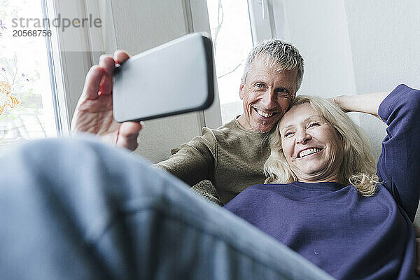 Smiling senior couple taking selfie at home