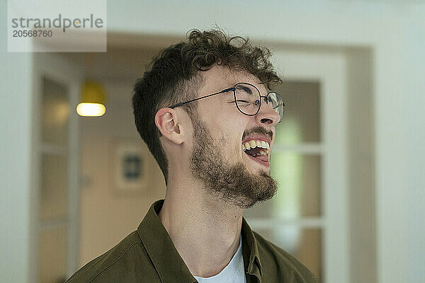 Young handsome man wearing eyeglasses laughing at home