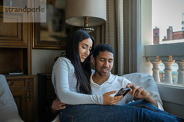 Young couple sharing smart phone together at home