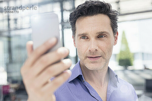 Confident handsome mature businessman using smart phone in airport