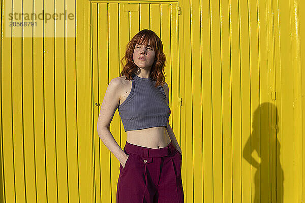 Beautiful confident redhead woman standing with hands in pockets on sunny day