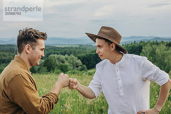 Smiling young man doing fist bump with friend on mountain