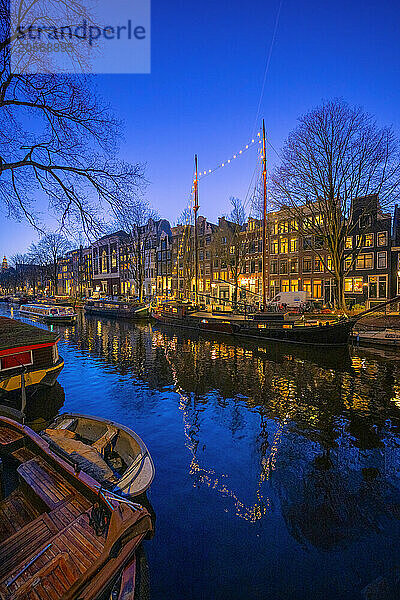 Boats moored on river at blue hour in Amsterdam