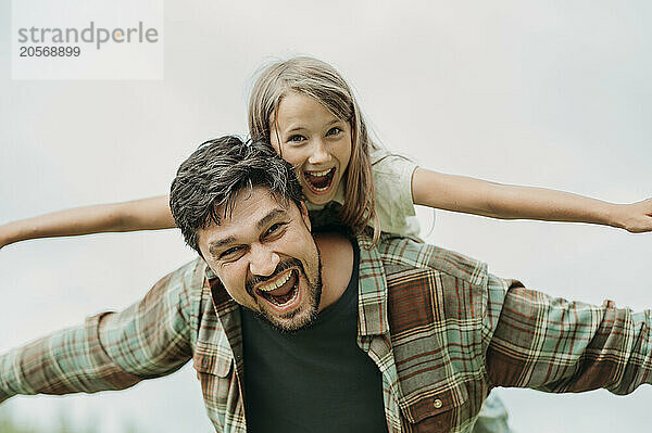 Cheerful girl on father with arms outstretched