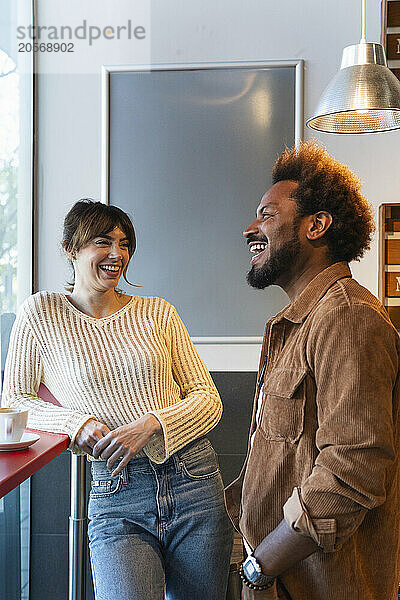 Cheerful multiracial couple standing at cafe