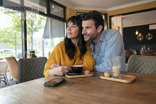 Smiling mature business couple sitting with coffee cups at cafe