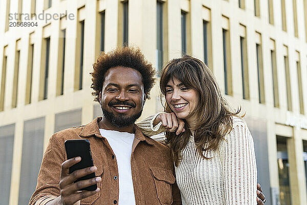 Smiling man taking selfie with girlfriend in city