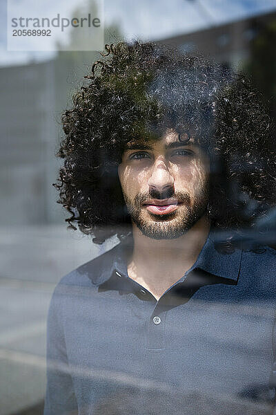 Confident businessman with curly hair looking out through window