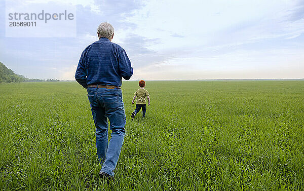 Senior man with grandson walking in field