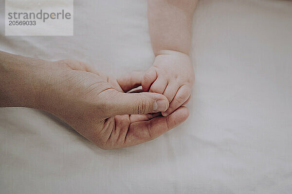 Hands of mother and son on bed