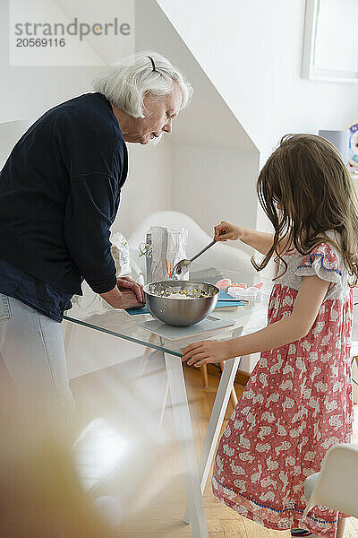 Girl and senior woman preparing food at home