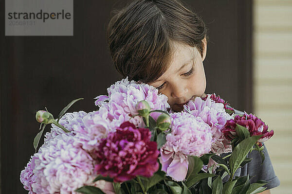 Cute boy with bouquet of peonies