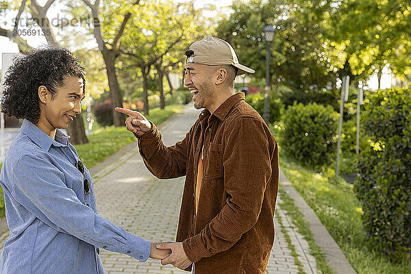 Happy boyfriend making fun of girlfriend and standing at park