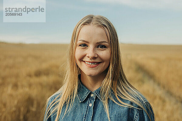 Happy blond hair young woman with piercing in wheat field